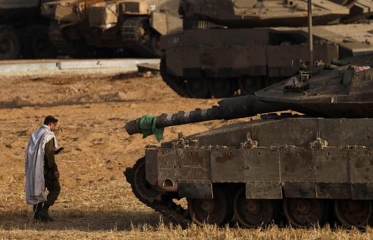 אפשר גם אחרת. חייל מתפלל ליד טנק בגבול הרצועה (צילום: REUTERS/Ronen Zvulun) גבול עזה חייל צה"ל מתפלל ליד טנק