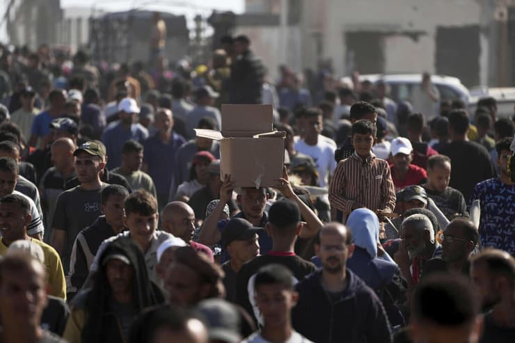 עזתים הולכים לקבל חבילות סיוע הומניטרי ברפיח (צילום: AP Photo/Abdel Kareem Hana) עזתים הולכים לקבל חבילות סיוע המוניטרי ברפיח
