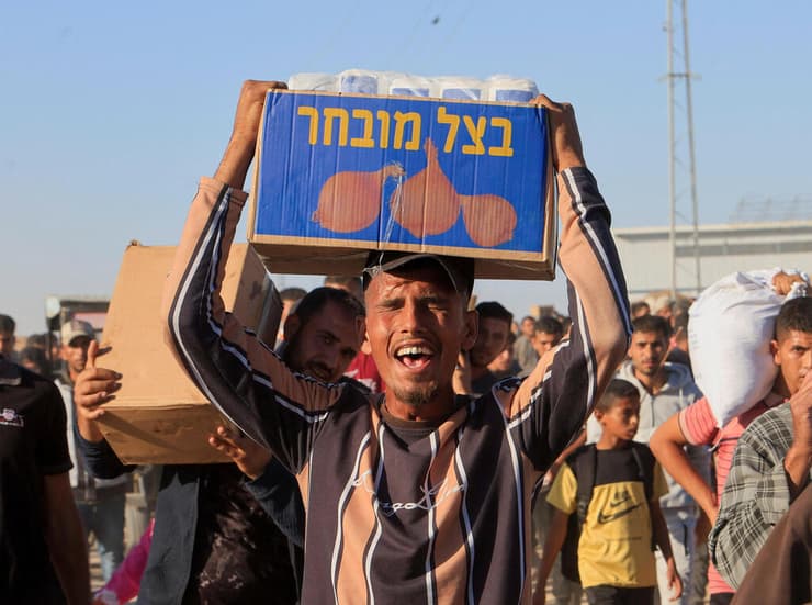 פלסטיני סוחב ארגז עם סיוע הומניטרי באזור חאן יונס, בחודש שעבר (צילום: REUTERS/Hatem Khaled) פלסטיני סוחב סיוע הומניטרי