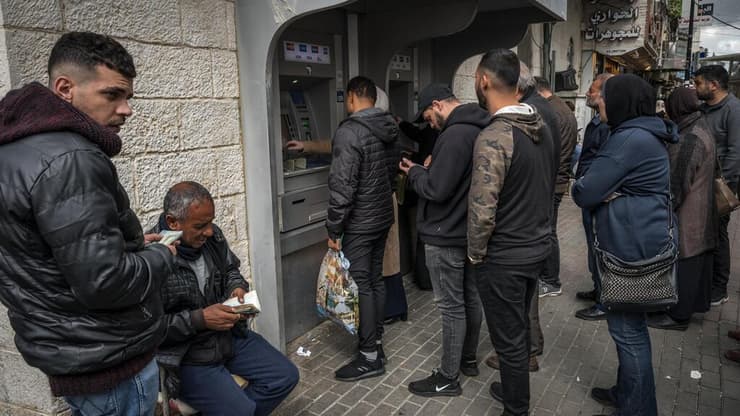 פלסטינים מחליפים כספים בבנק ברמאללה