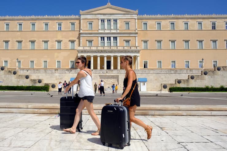 תיירות עם מזוודות מול בניין הפרלמנט באתונה