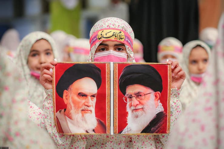 2023 איראן ילדה עם תמונות עלי חמינאי וקודמו בתפקידג המנהיג העליון רוחאללה חומייני באירוע לתלמידות שסיימו סמינר דתי 