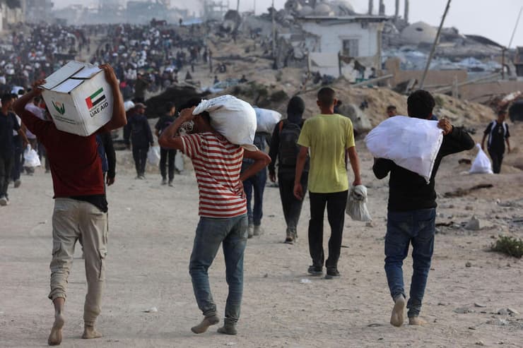 תושבי רצועת עזה נושאים סיוע הומניטרי בג'באליה. לא שואה, מלחמה (צילום: Omar Al-Qattaa / AFP) עזתים נושאים סיוע הומניטרי בג'באליה