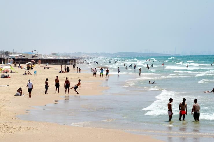 אנשים מבלים בחוף הים במהלך גל חום קיצוני