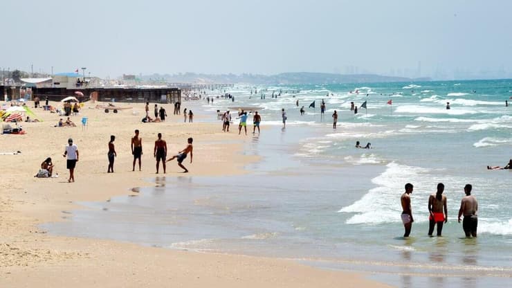 אנשים מבלים בחוף הים במהלך גל חום קיצוני