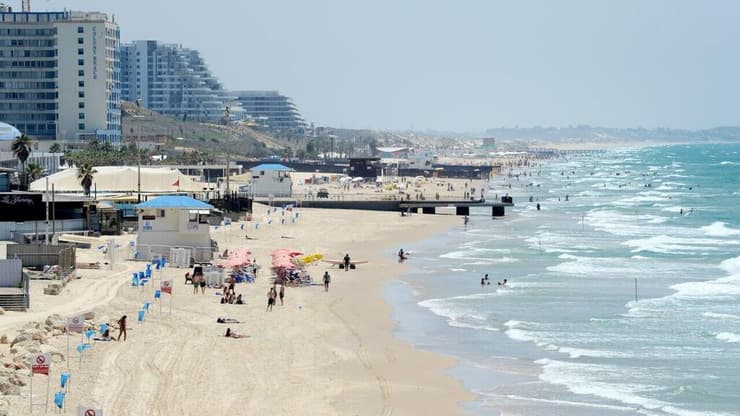 הקלה בעומסי החום (צילום: קובי קואנקס ) אנשים מבלים בחוף הים במהלך גל חום קיצוני