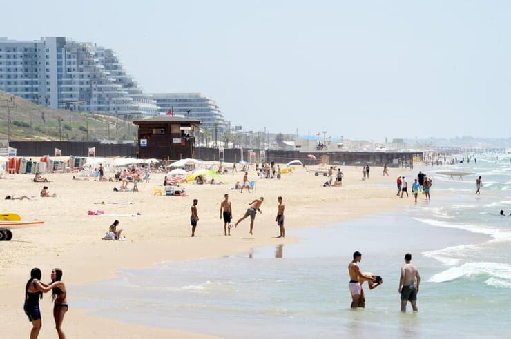 אנשים מבלים בחוף הים במהלך גל חום קיצוני