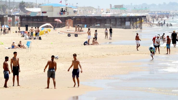 אנשים מבלים בחוף הים במהלך גל חום קיצוני