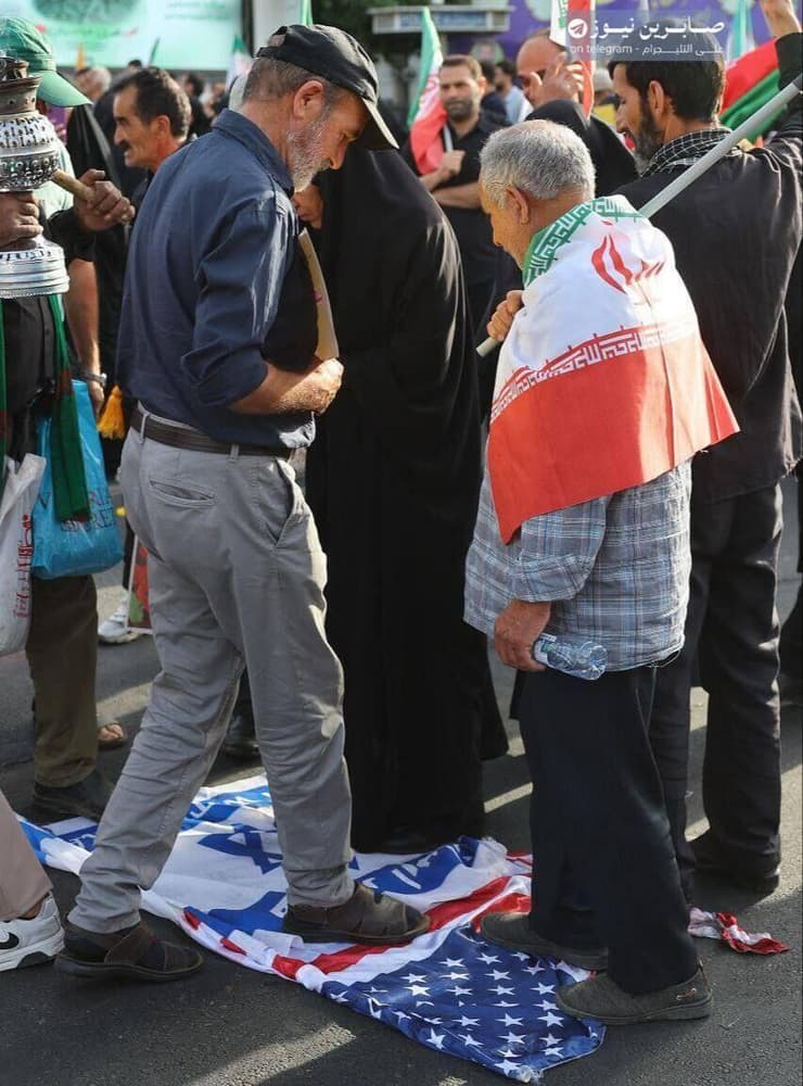 אזרחים איראנים דורכים על דגלי ישראל וארצות הברית