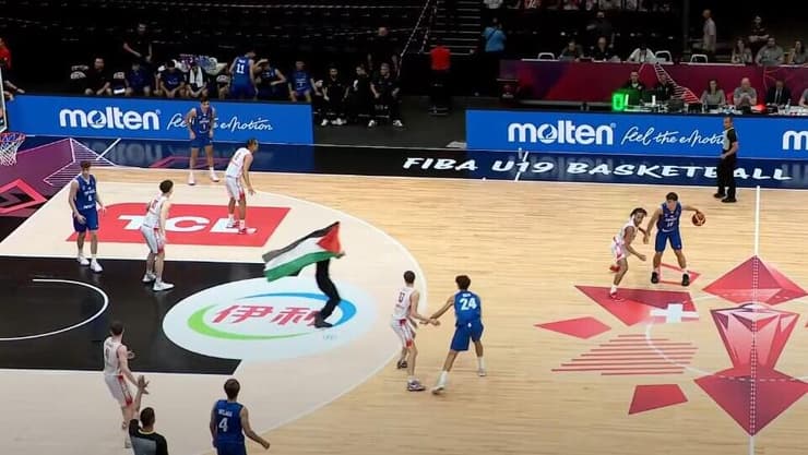 המפגין עם דגל פלסטין פורץ לפרקט (צילום מהטלוויזיה: ספורט 5) מפגין עם דגל פלסטין פורץ לפרקט