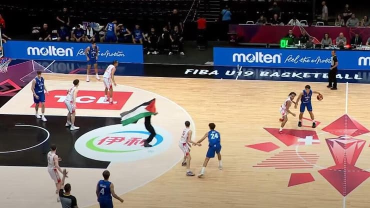 מפגין עם דגל פלסטין פורץ לפרקט במשחק של ישראל (צילום מהטלוויזיה: ספורט 5) מפגין עם דגל פלסטין פורץ לפרקט