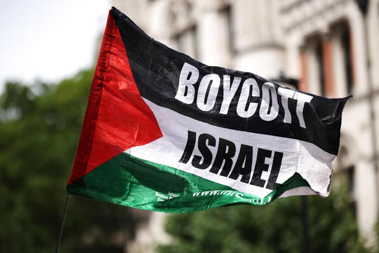 פעילים פרו פלסטינים פרו-פלסטינים מ Palestine Action עם דגל BDS הקורא ל חרם על ישראל בהפגנה מחוץ לבית המשפט ב לונדון נגד הכרזה על הארגון כארגון טרור בריטניה 