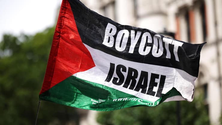 פעילים פרו פלסטינים פרו-פלסטינים מ Palestine Action עם דגל BDS הקורא ל חרם על ישראל בהפגנה מחוץ לבית המשפט ב לונדון נגד הכרזה על הארגון כארגון טרור בריטניה 