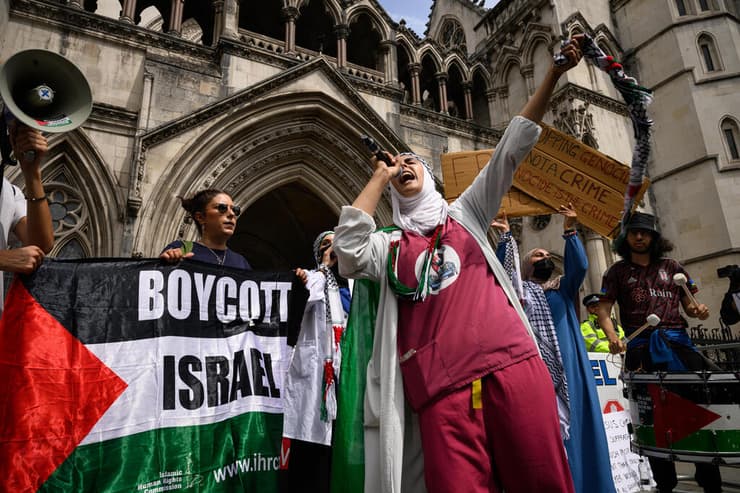 פעילים פרו פלסטינים פרו-פלסטינים מ Palestine Action עם דגל BDS הקורא ל חרם על ישראל בהפגנה מחוץ לבית המשפט ב לונדון נגד הכרזה על הארגון כארגון טרור בריטניה 