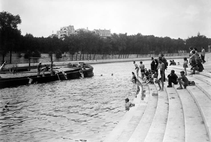אנשים שוחים בנהר הסן וקופצים מסירה חולפת סמוך לגשר ינה, ביולי 1945 בפריז, במהלך גל חום בקיץ של אותה שנה