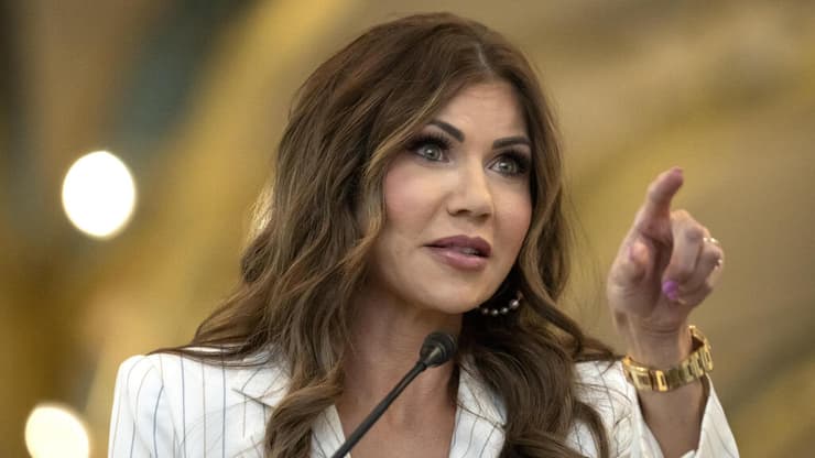 שרת ביטחון המולדת קריסטי נואם מכריזה על סיום נוהל חליצת הנעליים