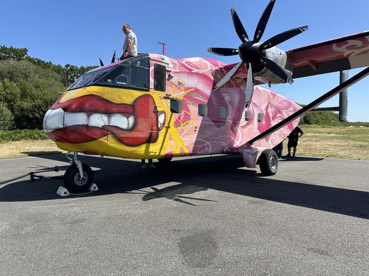 פיליפ הטייס יושב על מטוס הskyvan הוורוד. המטוס מותאם לצילום אווירי וצניחה חופשית