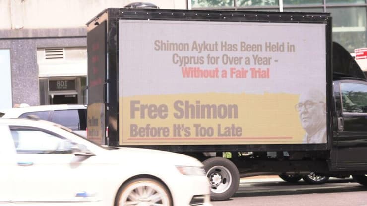 כרזת מחאה מחוץ לבניין האו"ם מחאה מול האו"ם למען שחרורו של שמעון אייקוט, אזרח ישראלי בן 75 הכלוא ללא משפט בקפריסין