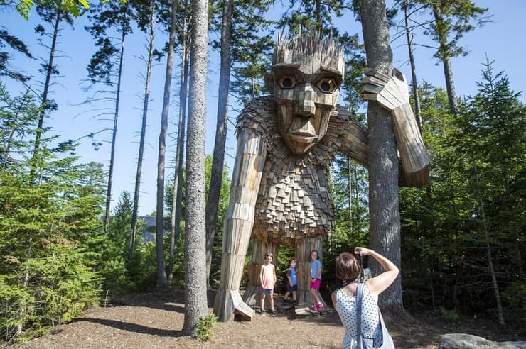 אנשים מצטלמים עם רוסקווה, טרול ענק שהוכן מעץ ממוחזר על ידי האמן הדני תומאס דמבו וצוותו, בגנים הבוטניים של מיין בארה"ב