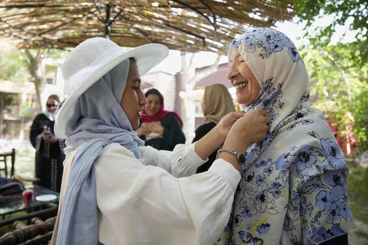 מריאם, צעירה אפגנית ביום ההכשרה הראשון שלה כמדריכת טיולים, מסייעת לתיירת האוסטרלית סוזן סנדרל, בת 82, לסדר את החיג'אב שלה בקאבול, אפגניסטן