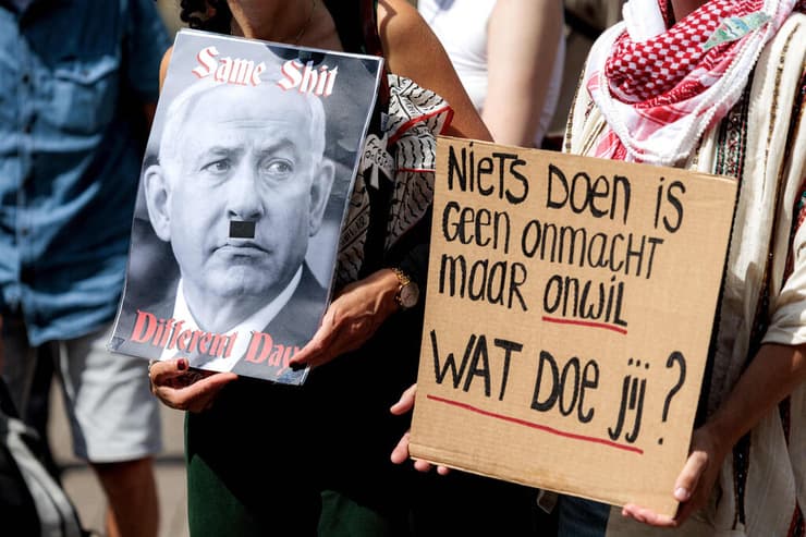שלט המשווה בין נתניהו לאדולף היטלר, בירת הולנד (צילום: Ramon van Flymen / ANP / AFP) הפגנה פרו פלסטינית באמסטרדם, הולנד
