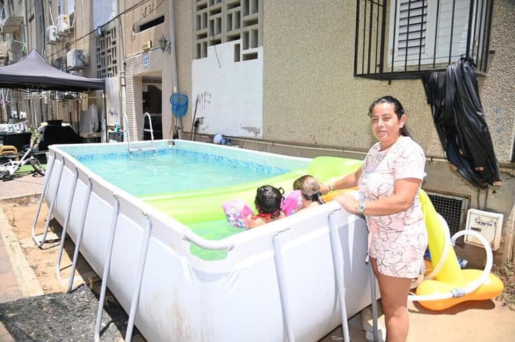 עם שניים מהילדים בבריכה מאולתרת בחצר הבניין