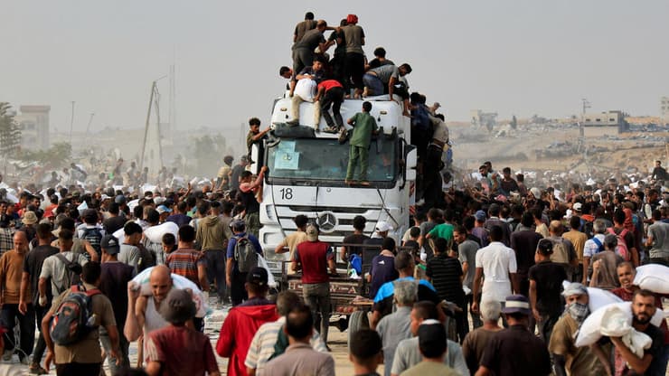 פלסטינים מתנפלים על משאית סיוע בעזה (צילום: REUTERS/Hatem Khaled) פלסטינים מתנפלים על משאית סיוע המוניטרי חאן יונס עזה