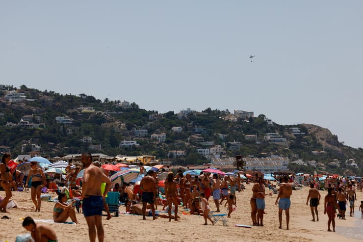 מתרחצים מביטים במסוק כיבוי אזור העיר טריפה ב ספרד שריפה שריפת יער