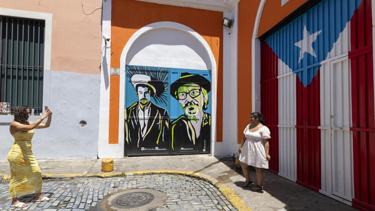 מעריצים מצטלמים ליד גרפיטי של באד באני