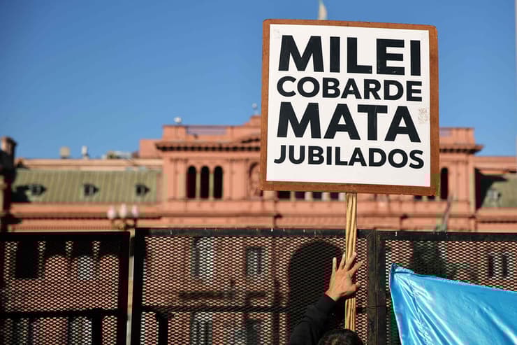 נשיא ארגנטינה חאבייר מיליי מחאת גמלאים מחוץ ל מעונו הרשמי הבית הוורוד שלט "מיליי הפחדן הורג פנסיונרים"
