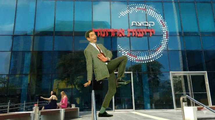 פרומפט פשוט ושתי תמונות: "מר בין על הרקע של בניין ידיעות אחרונות"