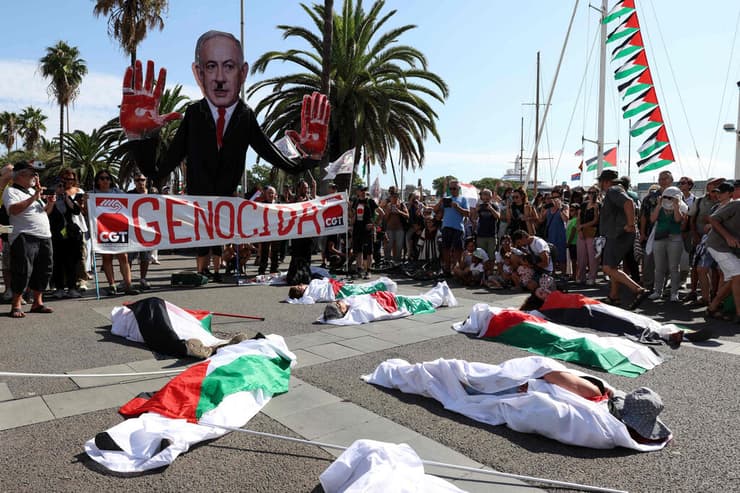 מיצג "פלסטינים הרוגים" בנמל ברצלונה לפני היציאה למשט (צילום: Lluis GENE / AFP) ספרד נמל ברצלונה מפגינים פרו פלסטינים פלסטיניים משט סומוד צומוד