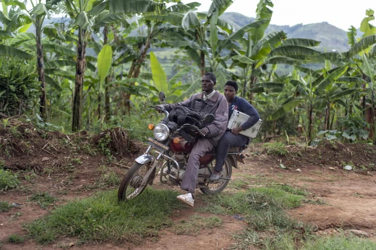 אפריקה זקנים אוגנדה אחות וויני קטווסיגיה על קטנוע מונית בדרך ל מטופל קשיש