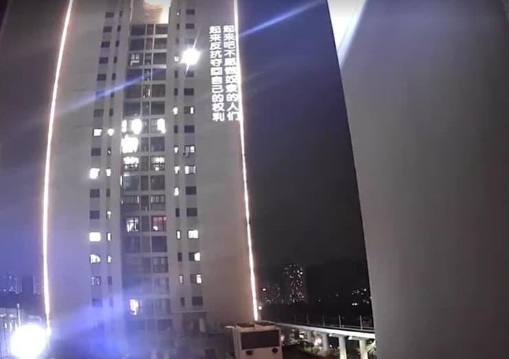 כתובת מחאה של צ'י מוקרנת על המגדל הסמוך, בתיעוד שהופץ ברשת מחאה נגד המפלגה הקומוניסטית על בניין ב סין הקרין וברח