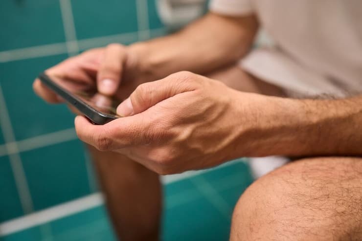 שימוש בסמארטפון בזמן ישיבה על האסלה מעלה את הסיכון לטחורים ב-46% (צילום: Shutterstock) גלילה בטלפון, שירותים