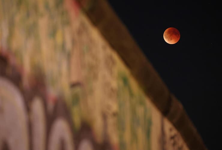 הירח על רקע קטע שנותר מחומת ברלין