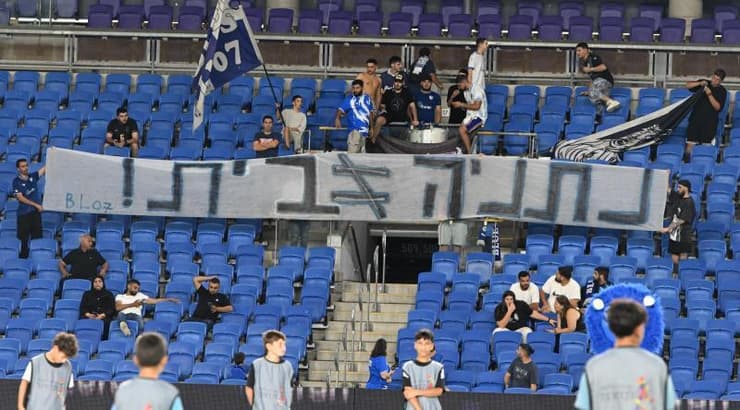 השלט של אוהדי עירוני קריית שמונה נגד האירוח בנתניה (ראובן שוורץ) השלט של אוהדי עירוני קריית שמונה נגד האירוח בנתניה