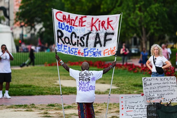 מתנגד ל צ'רלי קירק מפגין עם שלט שמאשים אותו בגזענות אחרי שנרצח ב וושינגטון הבירה ליד הבית הלבן ארה"ב 14 בספטמבר