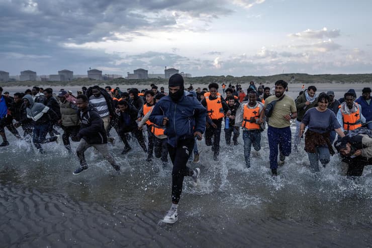 מהגרים רצים בניסיון לעלות על סירה ב חוף ב צרפת באזור גרבלין ליד קאלה לפני חציית תעלמת למאנש לכיוון אנגליה בריטניה 12 באוגוסט