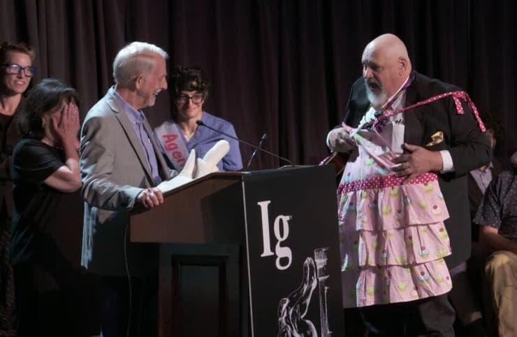 חתנים וכלות הפרס שחרגו מ-60 השניות שהוקצבו לנאום הזכייה נקטעו בעבר על ידי "מיס סוויטי-פו". השנה החליף אותה שר הטקס של פרסי איג נובל, גארי דרייפוס, בסינר ורוד | צילום מסך מתוך הטקס    