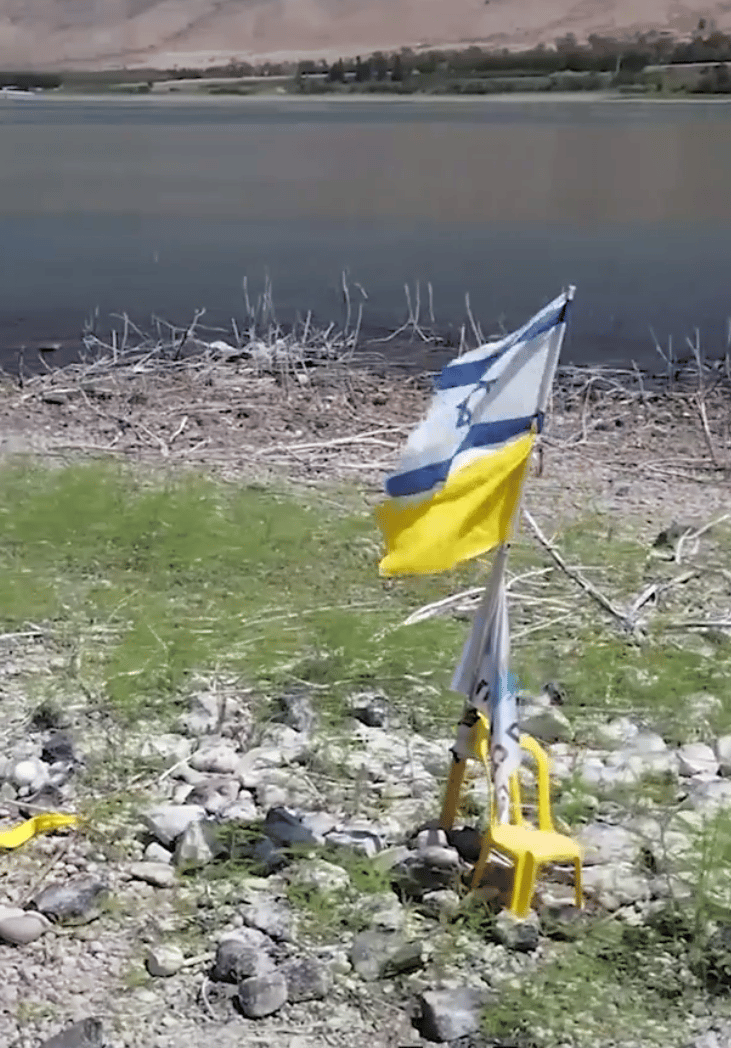 דגל ישראל לצד כיסא צהוב ודגל למען החטופים