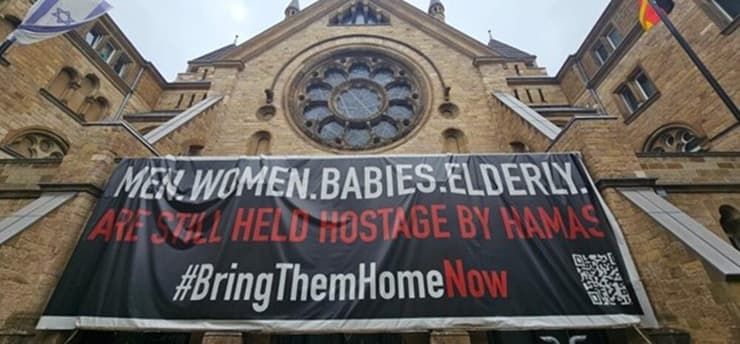 שלט לשחרור החטופים, שנתלה בחזית בית הכנסת הגדול ברחוב Roonstraße בקלן