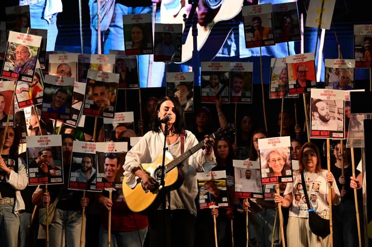 נינט שרה בעצרת, כשברקע עומדים שורדי שבי