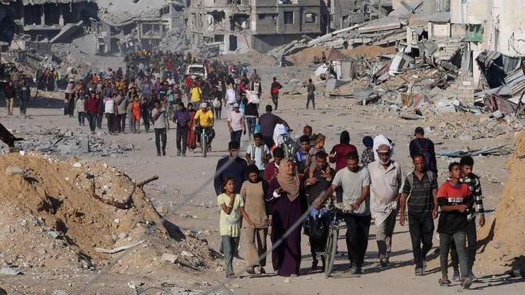 עקורים פלסטינים חולפים על פני הריסות