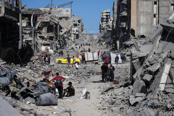 עקורים פלסטינים חולפים על פני הריסות ביתם (צילום: AP Photo/Abdel Kareem Hana) עקורים פלסטינים חולפים על פני הריסות