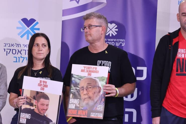 הוריו של מתן אנגרסט נושאים שלטים של החללים החטופים (צילום: מוטי קמחי) הצהרת משפחות שורדי השבי באיכילוב