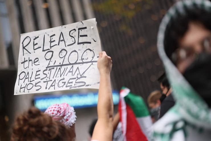 שלט בהפגנה אנטי-ישראלית בניו יורק שקורא לשחרר את האסירים הפלסטינים וקורא להם "חטופים"