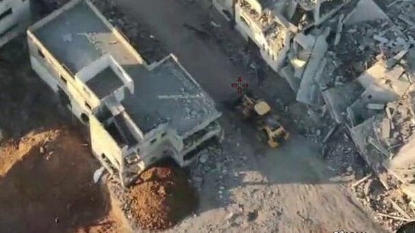 השקית הלבנה מועברת מהבניין לבור הענק אנשי חמאס מביימים הימצאות שרידי גופת חלל, בנוכחות אנשי צלב אדום