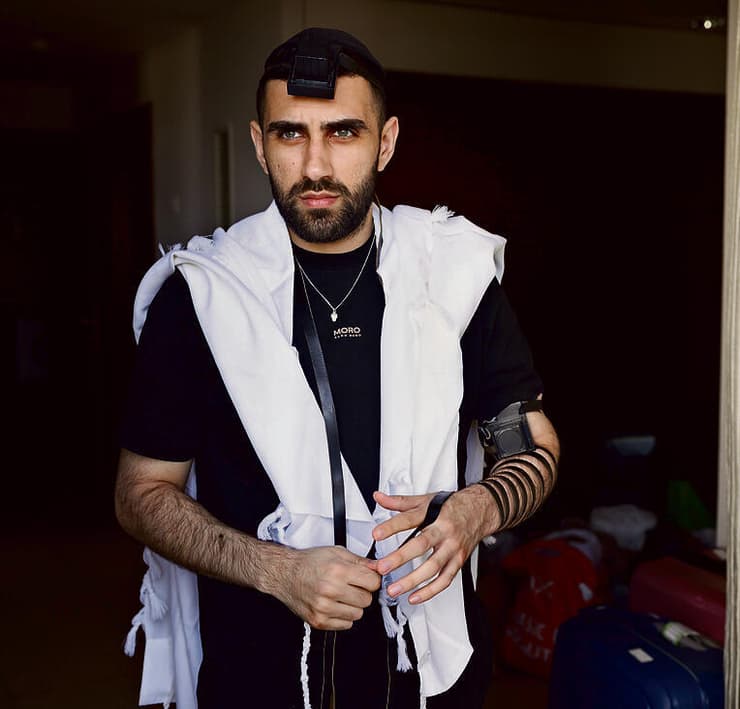 ”ביקשתי סליחה מבורא עולם שיצאתי למסיבה בשבת". מניח תפילין בחדרו הזמני, לפני השיבה הביתה לדימונה yk14559858