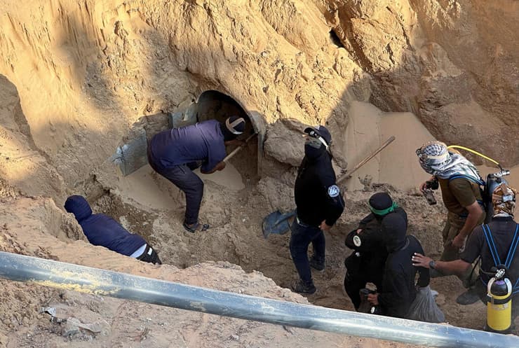 מחבלי חמאס בפתח מנהרה ברצועה, אתמול. בישראל סבורים שארגון הטרור יכול להשיב חלק גדול (צילום: REUTERS/Haseeb Alwazeer) חאן יונס עזה מחבלי חמאס מוציאים גופה מתוך מנהרה